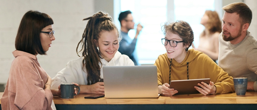 Bild von 4 jungen Leuten mit Laptop und Kaffeehäferl beim Gespräch